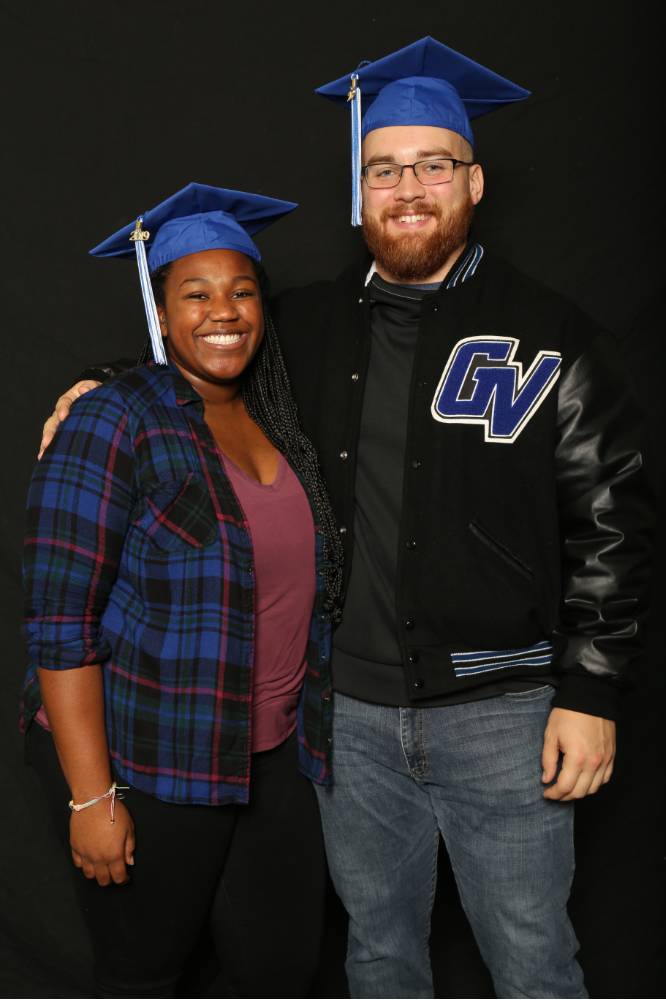 two friends in graduation caps with gvsu varsity jacket